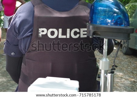 Policeman on a motorbike wearing a bulletproof vest with police word.