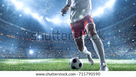 Soccer player kicks the ball on the soccer stadium. He wear unbranded sports clothes. Stadium and crowd made in 3D. Royalty-Free Stock Photo #715790590