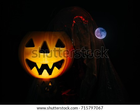 Halloween Concept,
Jack O'Lantern Halloween Pumpkin, Ghost Silhouetted Figure with mystic moonlit night in fog on dark background