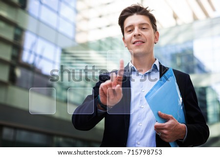 Man in suit touching screen on the background of modern buildings
