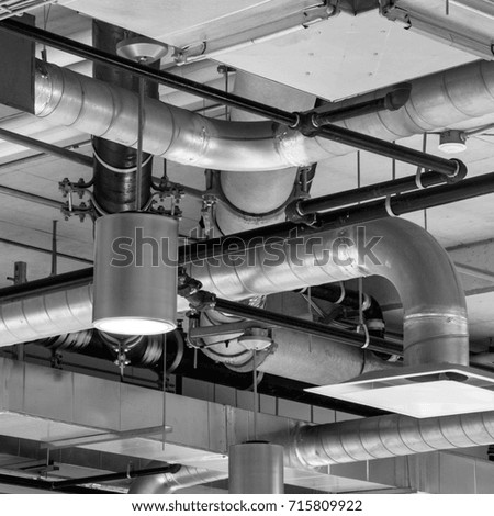 Industrial building ceiling with pipes - black and white square photo