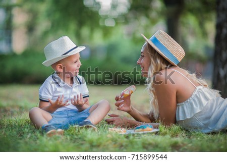 happy blond mom with her little son enjoying nature on a background of green leaves.