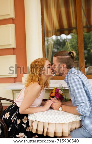 Happy young couple. Boyfriend and girlfriend sitting in cafe in the daytime while looking into each other's eyes. Beautiful woman is going to kiss her beloved