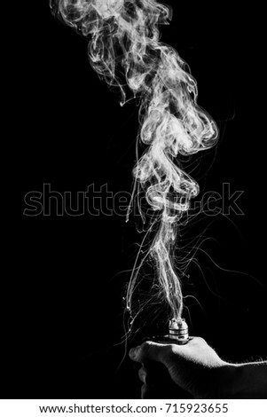 isolated. Black and white Hand holding electronic cigarette. Abstract art smoke moving on black background. 