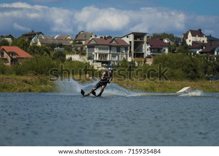 young male athlete glides on water skis on the waves on the lake