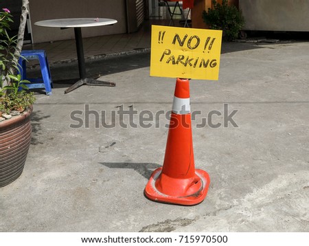Makeshift no parking sign on a cone along the pavement