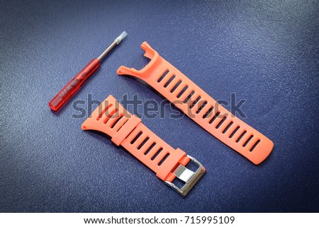 Orange watchband rubber skin & repairing tool kit for adjusting watchband on isolated blue background.