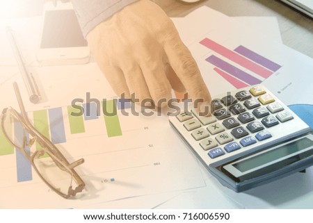 Business documents on office table with laptop, smart phone  and graph financial and man working in the background. Business concept.