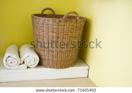 big basket and towels with yellow wall.