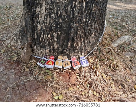 Shackled alphabetical Cartoons each Named letters: H,A,T,R,E,D leaning against a tree.