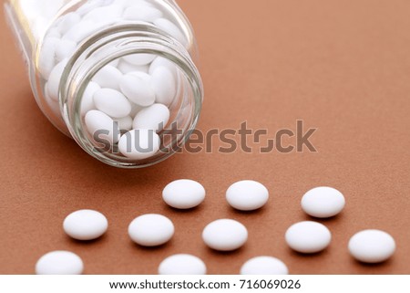 medical pills and glass bottle on brown background