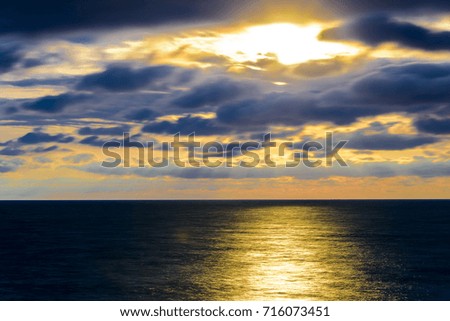 A long exposure seascape landscape with sun, clouds and sparkling sea.