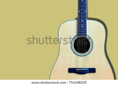 Wooden guitar on yellow background.