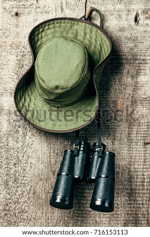 The green Ranger's hat and binoculars on wooden background