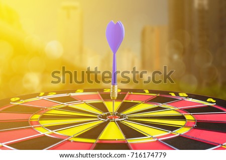 Blue dart arrow on center of dartboard  with city and sunset background.,idea business goal.