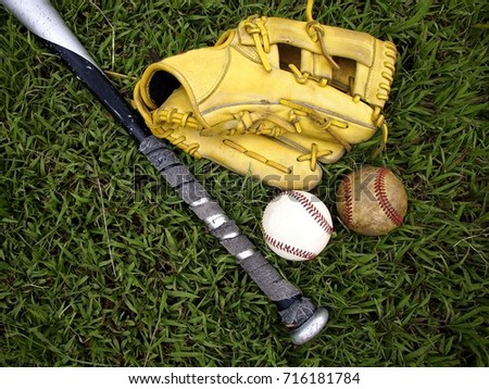 Photo of a baseball gloves, baseball and a baseball bat on the grass
