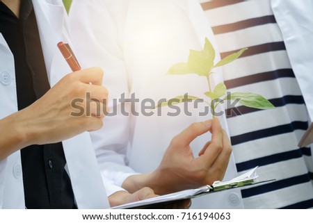 Closeup two young Biology researcher with a clipboard, pen and tablet examining plant leaf for keep specifics data in a nature park, Copy space