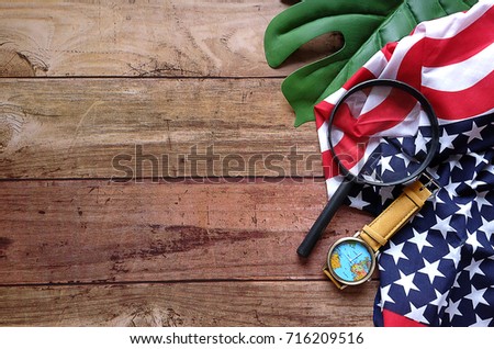 Top view Handkerchief look like USA flag with map watch and Magnifying glass on green leave and wood pattern,  For concept find America on Columbus Day,Have copy space.