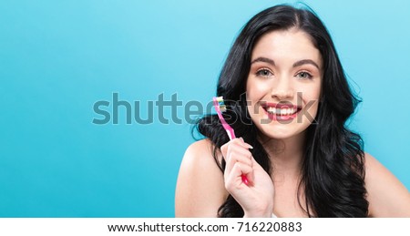 Young woman holding a toothbrush on a solid background