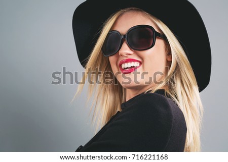 Beautiful young blonde woman in a black coat, hat and sunglasses