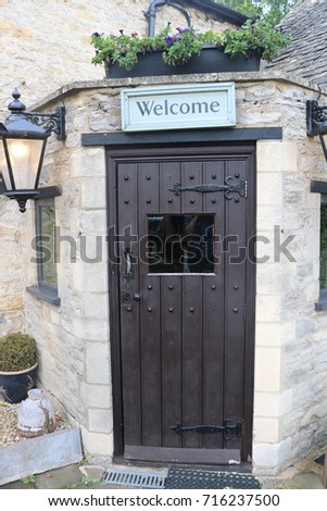 Welcome sign about old traditional British inn wooden door with outside lamp