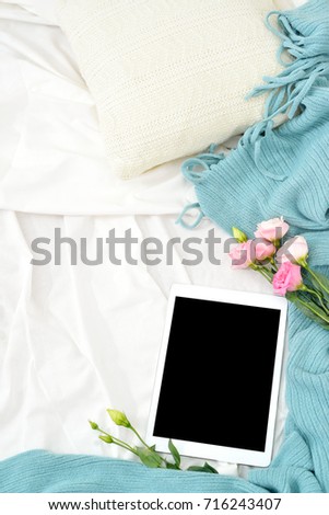 Flat lay tablet and flowers on white blanket with turquoise plaid. Window light, space for text blog, posts
