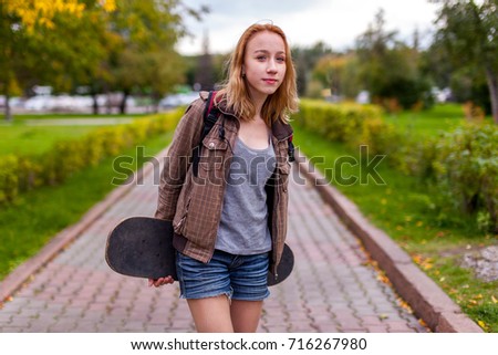 teen girl in park with skateboard in hands