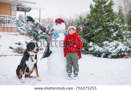happy boy and his black dog in winter in the snow, outdoor games, family, best friends, smiling kid and Large Swiss Mountain Dog on the background of  winter landscape, winter holidays, christmas