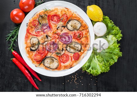 Fresh tasty pizza with vegetables on black wooden surface. Top view. Free space