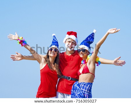 Concept: New Year on the beach. The company - a boy and two girls in clothes for the new year enjoying sunset on the beach