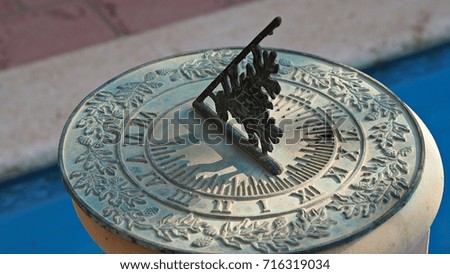 A green vintage sun dial or sun clock above swimming pool. 