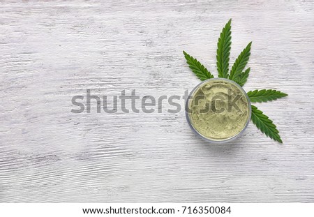 Jar of hemp lotion on wooden background Royalty-Free Stock Photo #716350084