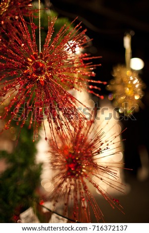 A photo of red starburst ornaments hanging from a Christmas tree.