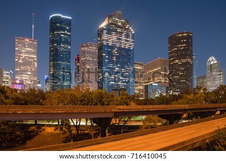 Downtown Houston from Buffalo Bayou Park at blue hour. Highway car light trails in front and skyscrapers from central business district in background. Transportation, architecture and travel concept