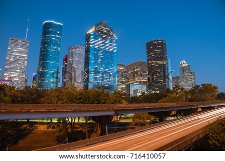 Downtown Houston from Buffalo Bayou Park at blue hour. Highway car light trails in front and skyscrapers from central business district in background. Transportation, architecture and travel concept