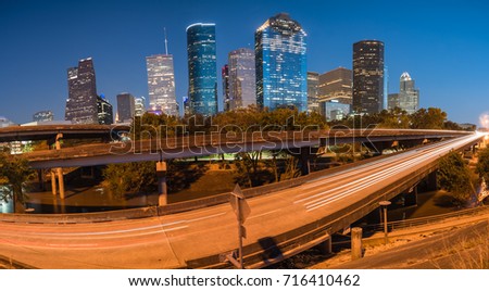 Panorama downtown Houston from Buffalo Bayou Park at blue hour. Highway car light trail in front, skyscrapers from central business district in background. Transportation, architecture, travel concept