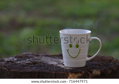 Conceptual Photography: Hot drink in smiling mug with nature background