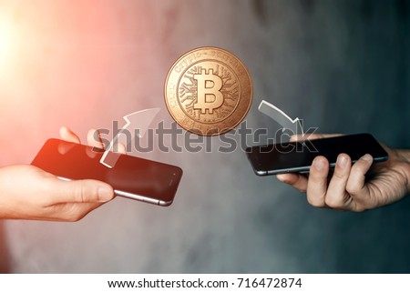 Gold coin Bitcoin payment from phone to phone, hands and TVs close-up. The concept of crypto currency. Blockchain technology. Mixed media.