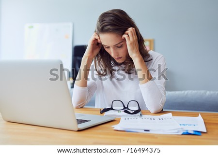stressed young entrepreneur holding her head and looking down because of stress and headache in office Royalty-Free Stock Photo #716494375