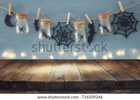 Halloween holiday concept. Empty old wooden table in front of mason jars with spiders and baths decorations. Ready for product display montage