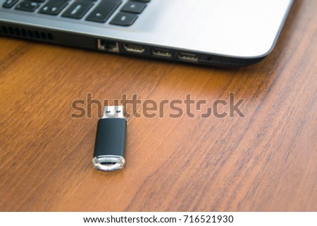 USB memory stick or flash drive and laptop computer on wooden desk