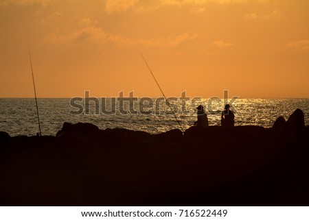 Two fishermen at sunset at the Italian sea