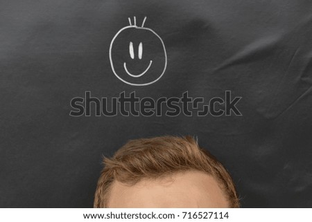 head in front of a board with a smiley drawn on it 