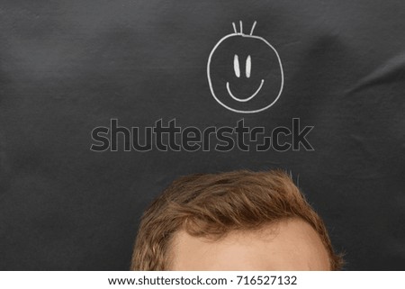 head in front of a board with a smiley drawn on it 