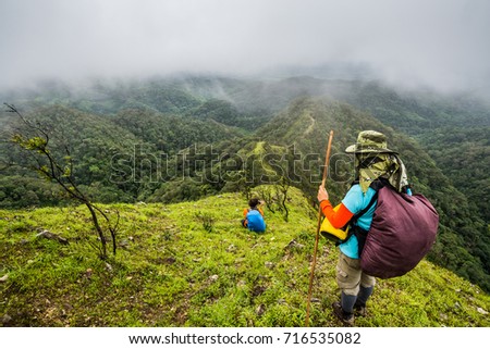 Hikers with backpacks on the mountain ridge is looking at the mountain peak.