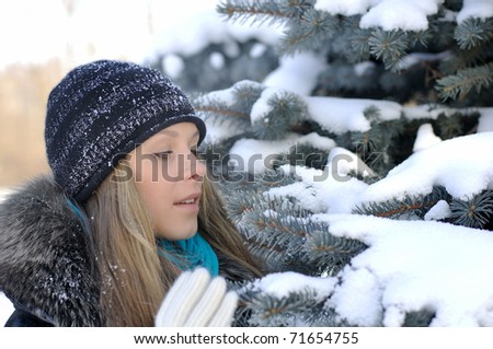 Nice girl looking at snow-covered fir branches