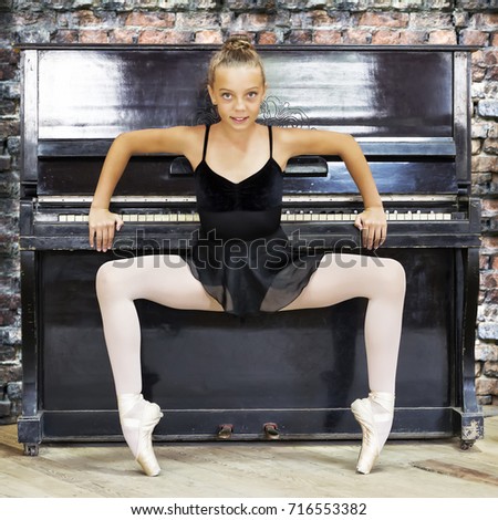 A ballerina and an old piano. Background made of old brick. Music, dance, education.