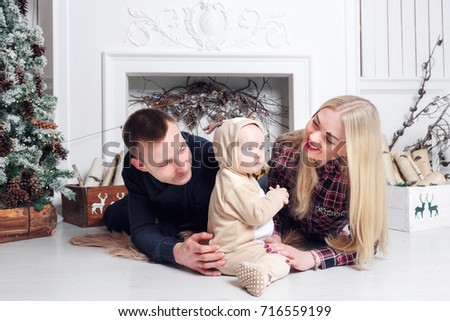 Happy family at Christmas. The parents and the baby lying on the floor and smiling.