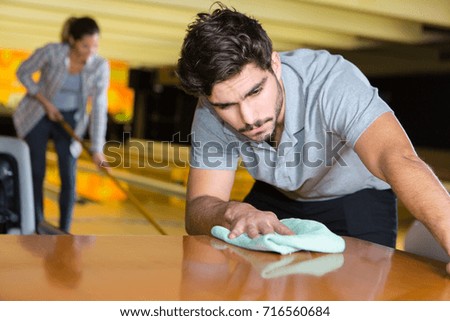young man cleaning table at cafe