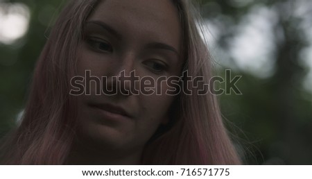 teen girl with purple hair standing in town at night looking at mobile phone